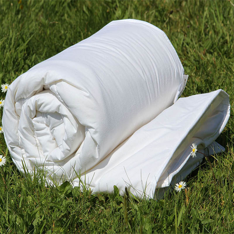 Devon Wool Duvet rolled up on the grass with daisies